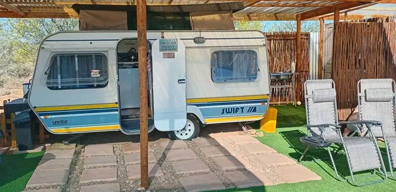 The front of the caravan with two reclining loungers and a reed screen on one side