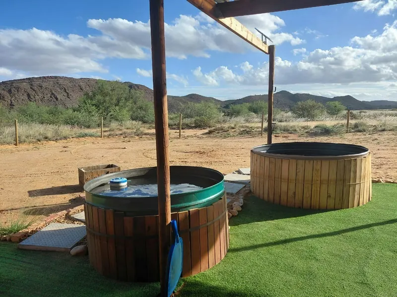 Two timber hot tubs on a small lawn at Karoo Stone Camper with the Klein Karoo mountains on the horizon